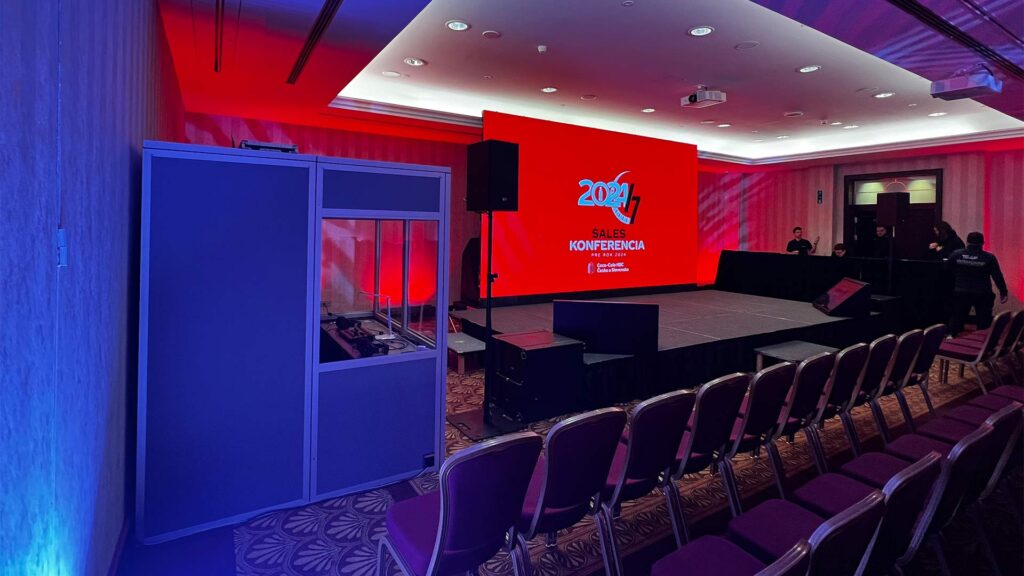 Vortragsraum mit roter Beleuchtung und Podium.