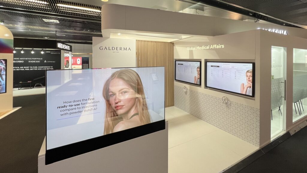 Messestand mit Bildschirmen und Werbung für Kosmetika