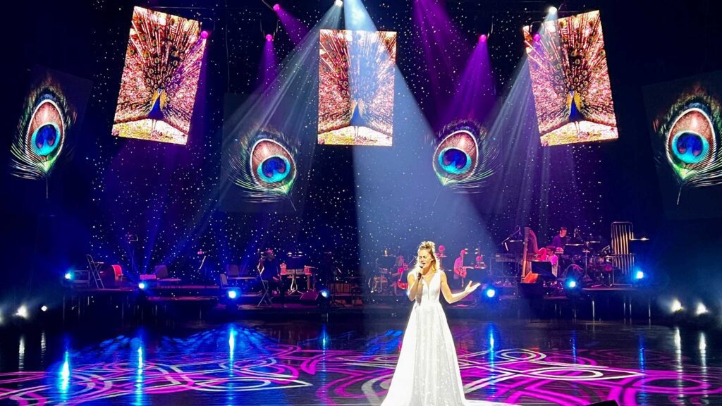 Sängerin auf einer bunten Bühne mit Beleuchtung.