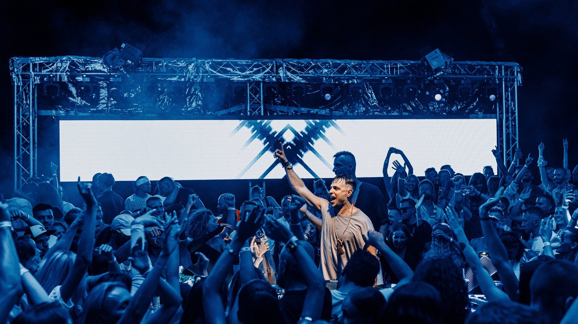 Ein DJ tritt vor einem Publikum auf einer Konzertbühne auf.