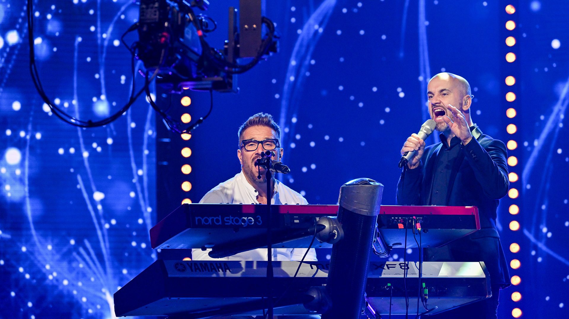 Die Musiker spielen und singen gemeinsam auf der Bühne.