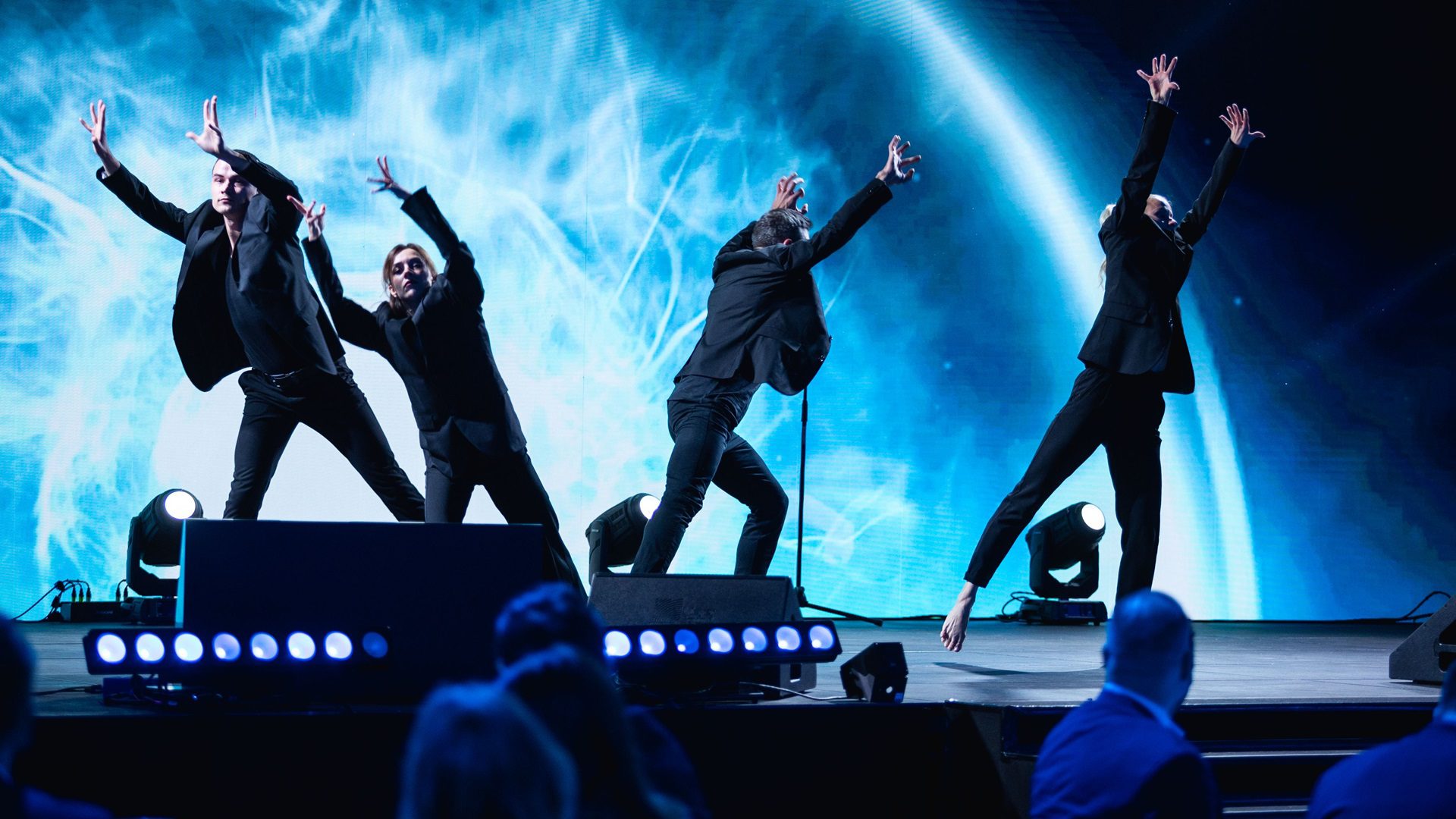 Tanečníci na jevišti před vesmírným pozadím.