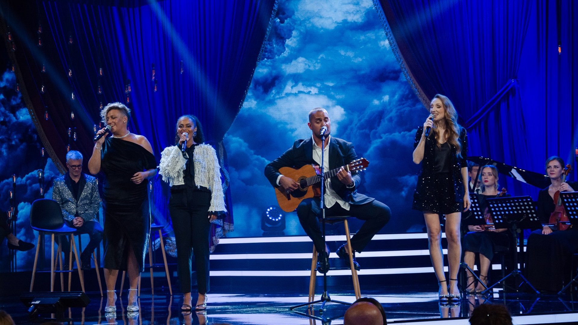 Eine Gruppe von Sängern tritt auf einer beleuchteten Bühne auf