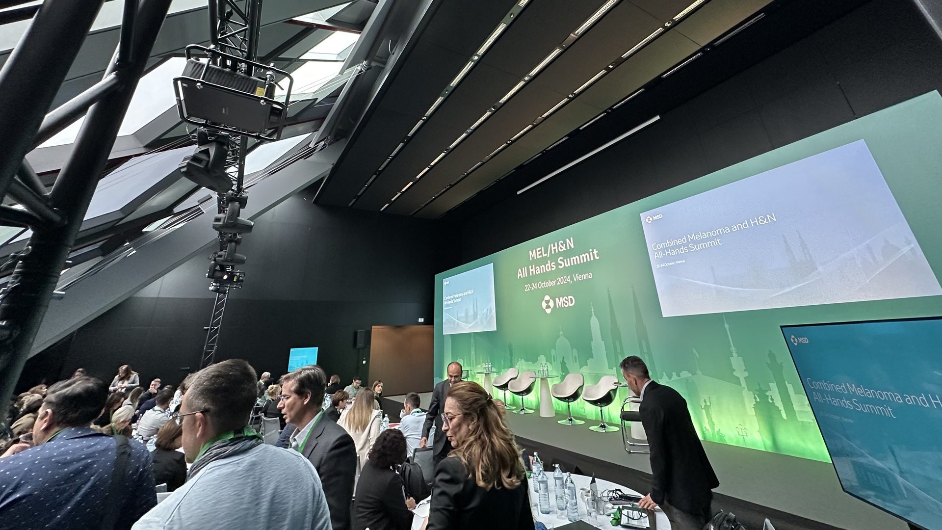 Eine Konferenz mit Menschen und Präsentationen auf der Bühne.