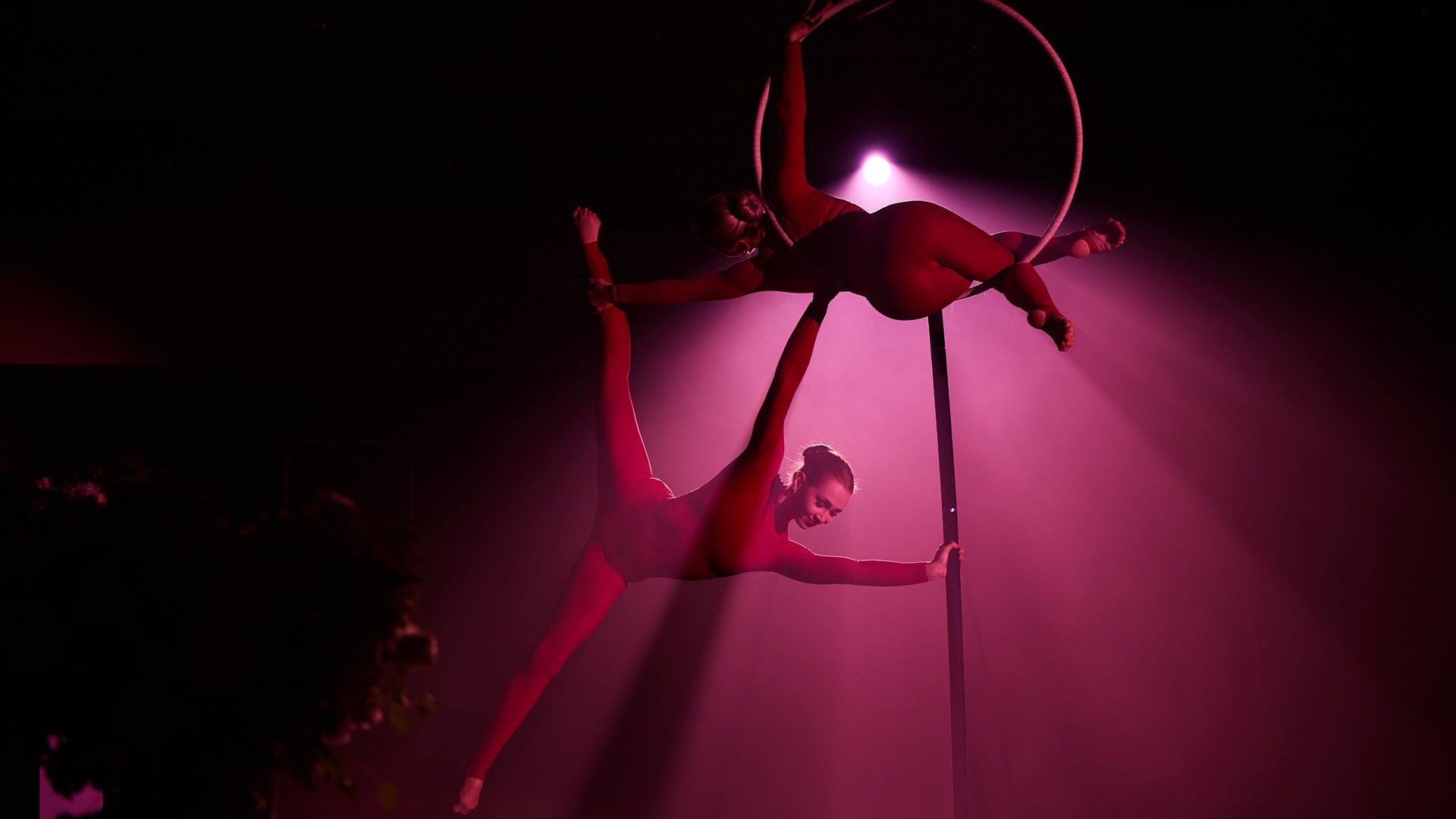 Akrobati na kruhoch pod fialovým osvetlením.