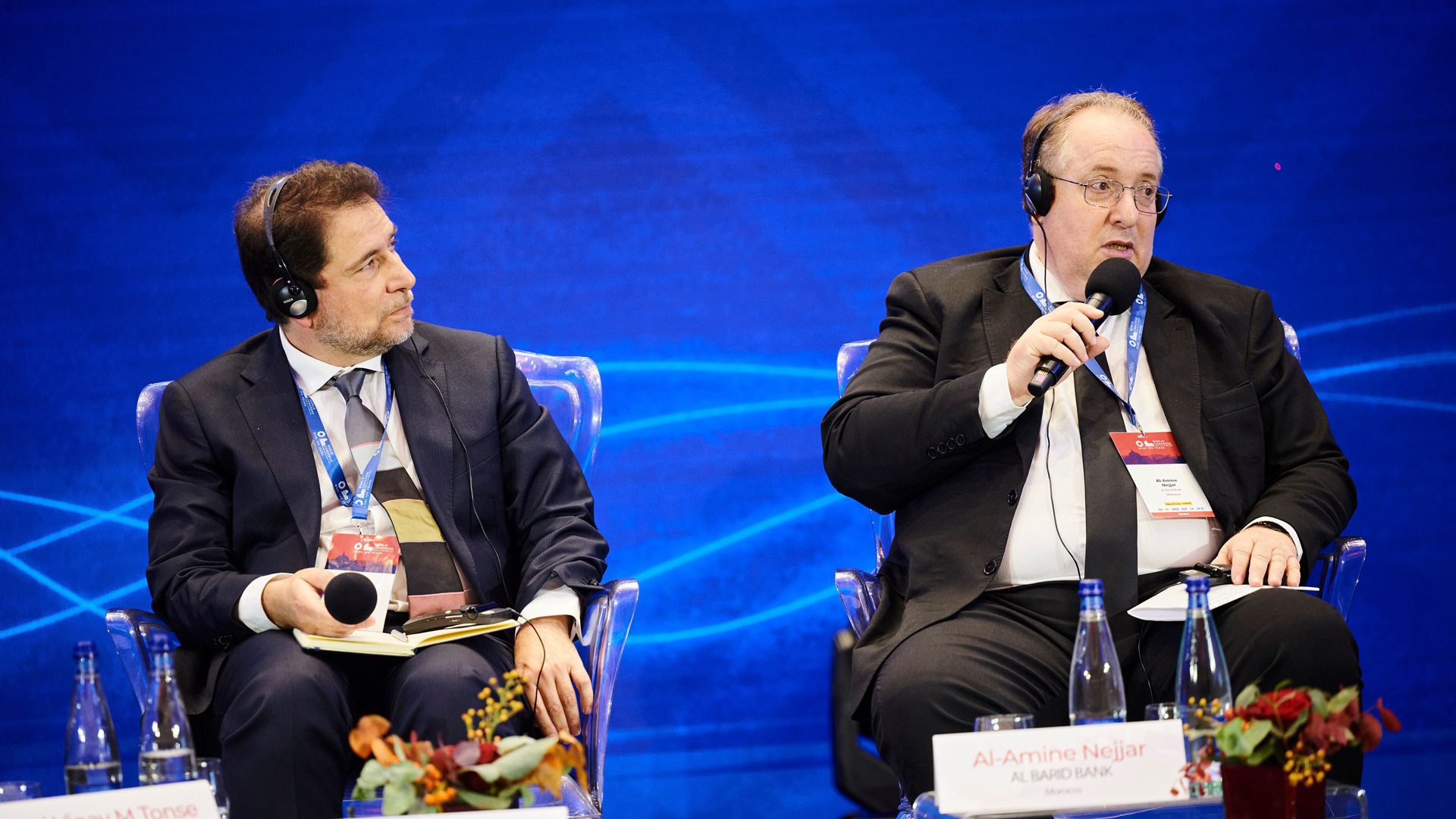 Menschen diskutieren auf einer internationalen Konferenz mit Mikrofonen.