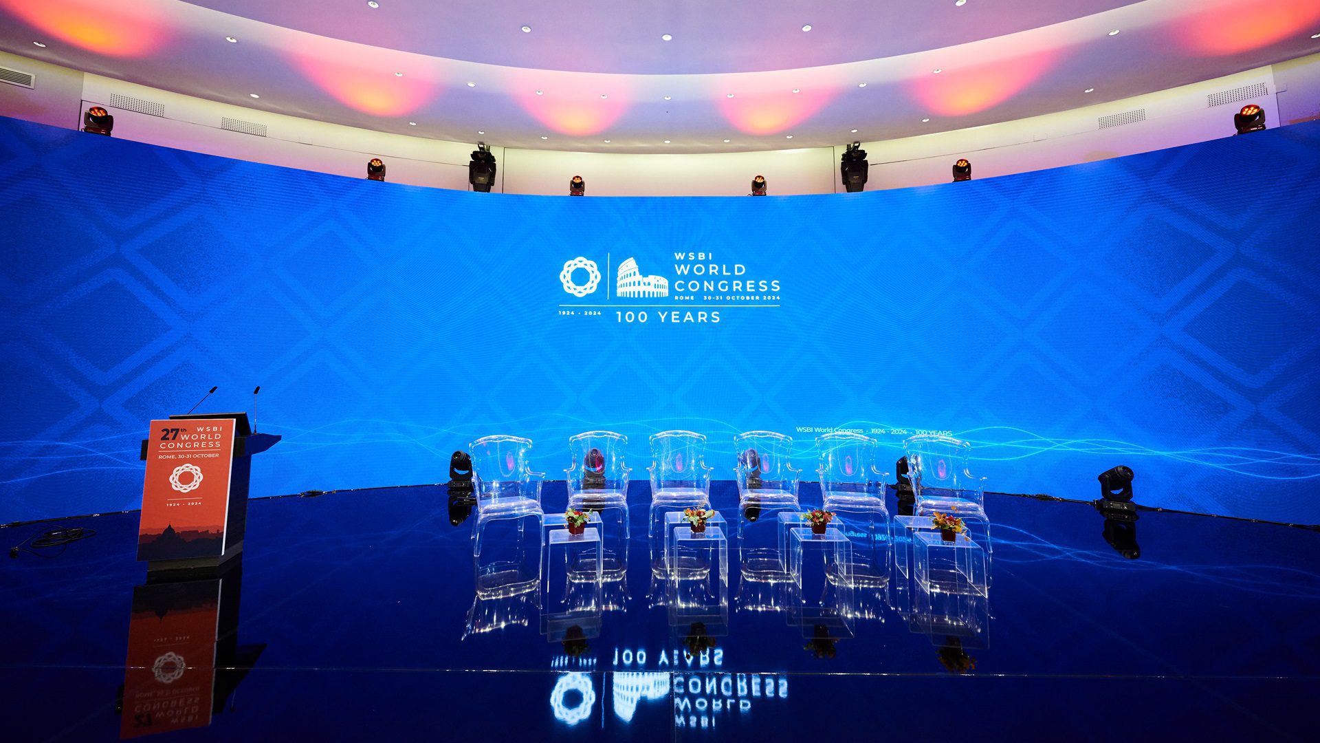 Konferenzraum mit Stühlen und Großbildschirm.