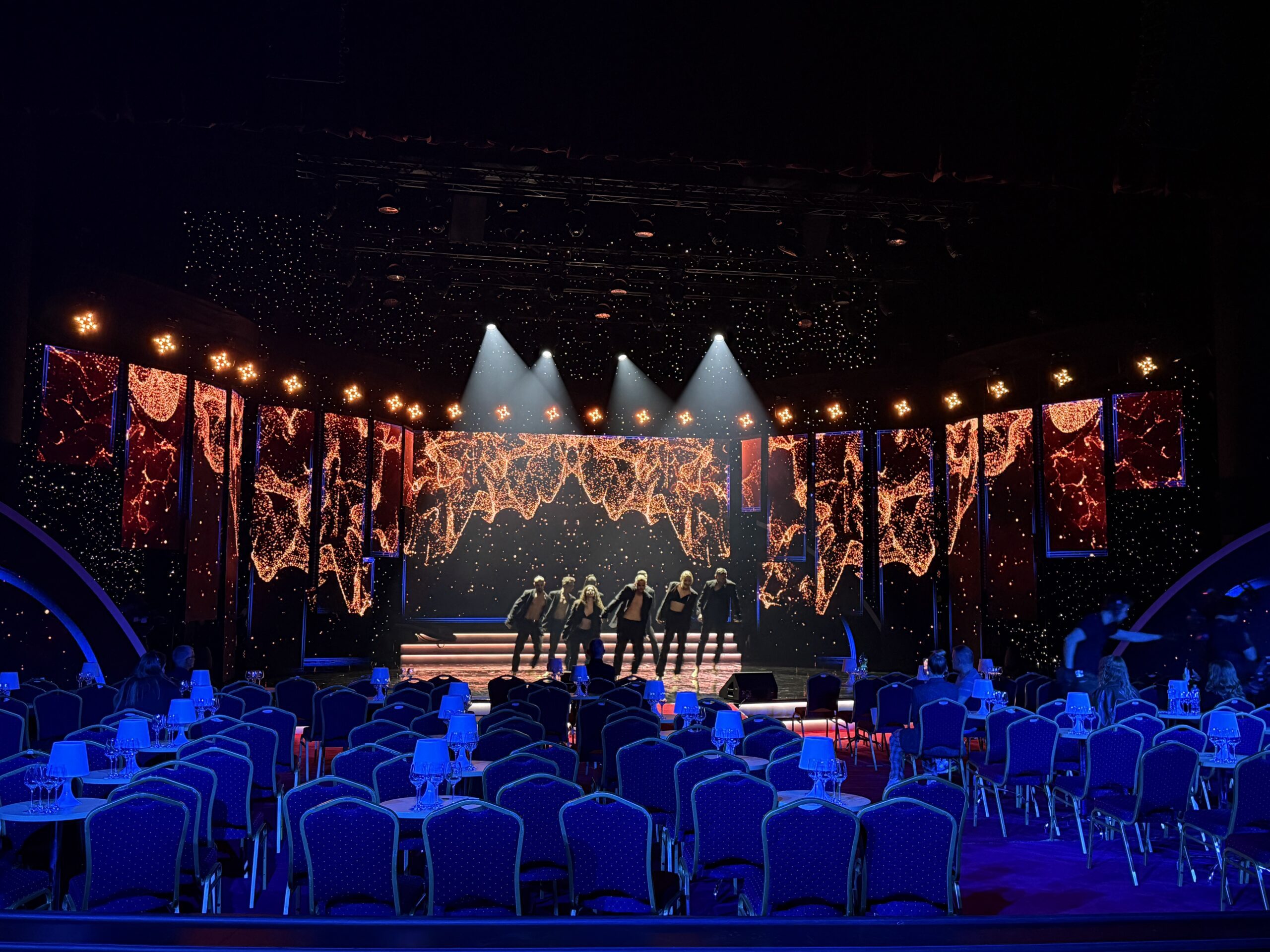 Tanzaufführung auf einer beleuchteten Bühne mit LED-Bildschirmen und einem vorbereiteten Zuschauerraum