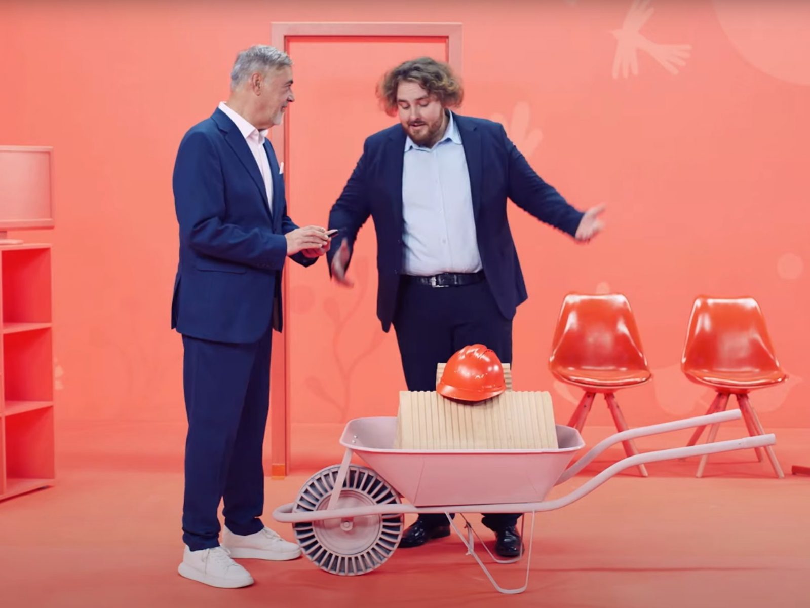 Muži diskutujú vedľa fúrika v oranžovej miestnosti.