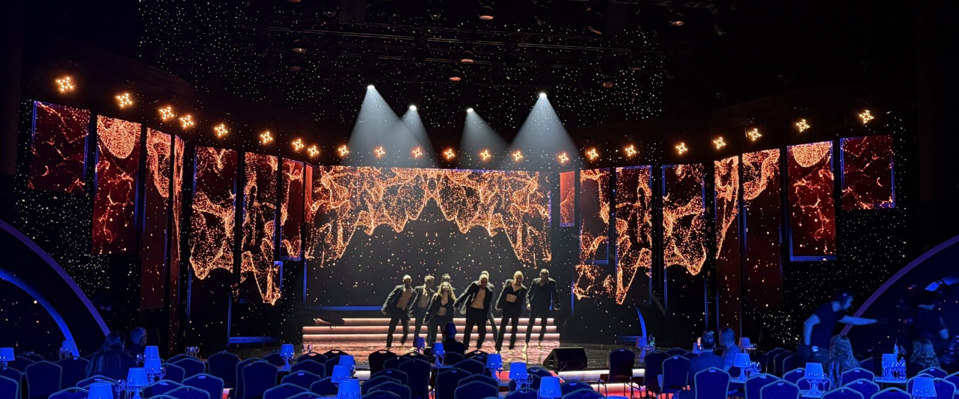 Tanzaufführung auf einer beleuchteten Bühne mit LED-Bildschirmen und einem vorbereiteten Zuschauerraum
