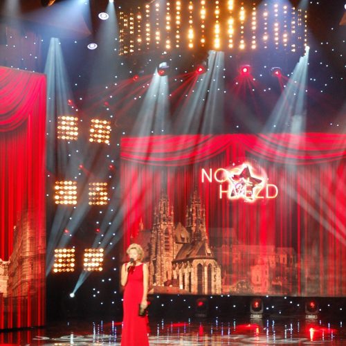 Frau auf einer beleuchteten Bühne mit roten Vorhängen